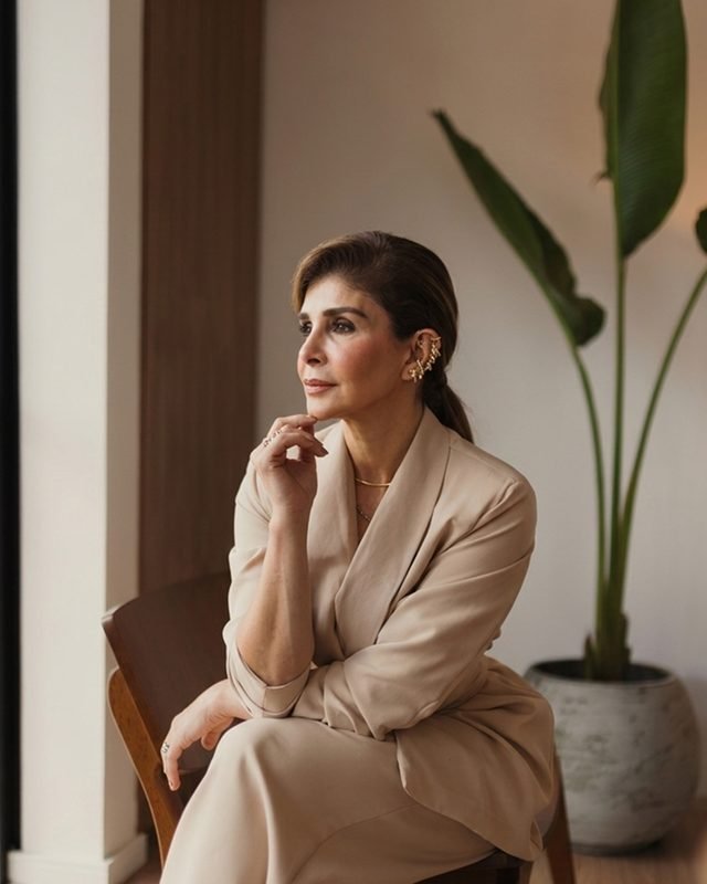 Dra. Zarifa Khoury sentada em uma poltrona, em ambiente claro com uma planta ao fundo